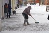 Поки нема покупців продавчиня чистить сніг поблизу свого магазину