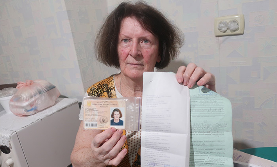 Елеонора Артем’єва показує пенсійне посвідчення і постанову про штраф