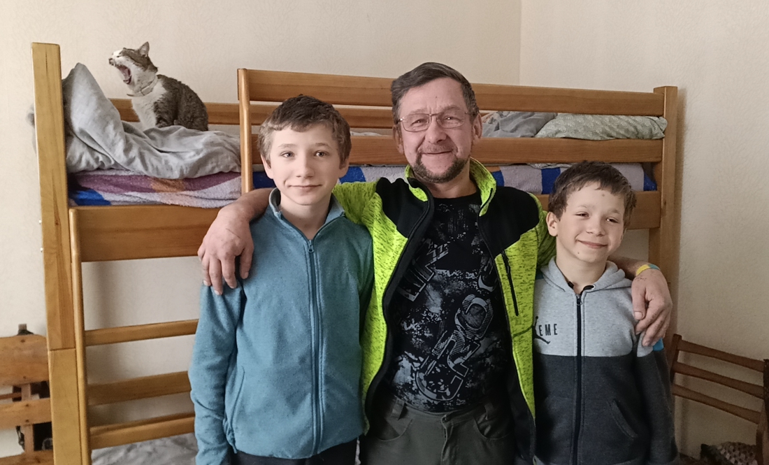 Олександр Рибенок з синами Нікітою (зліва) та Віктором (справа). Позаду двоярусне ліжко хлопців і кіт Мурчик