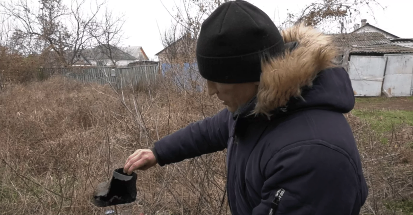 Олександр Коцюба тримає шматок гумового чобітка, який розірвало внаслідок вибуху