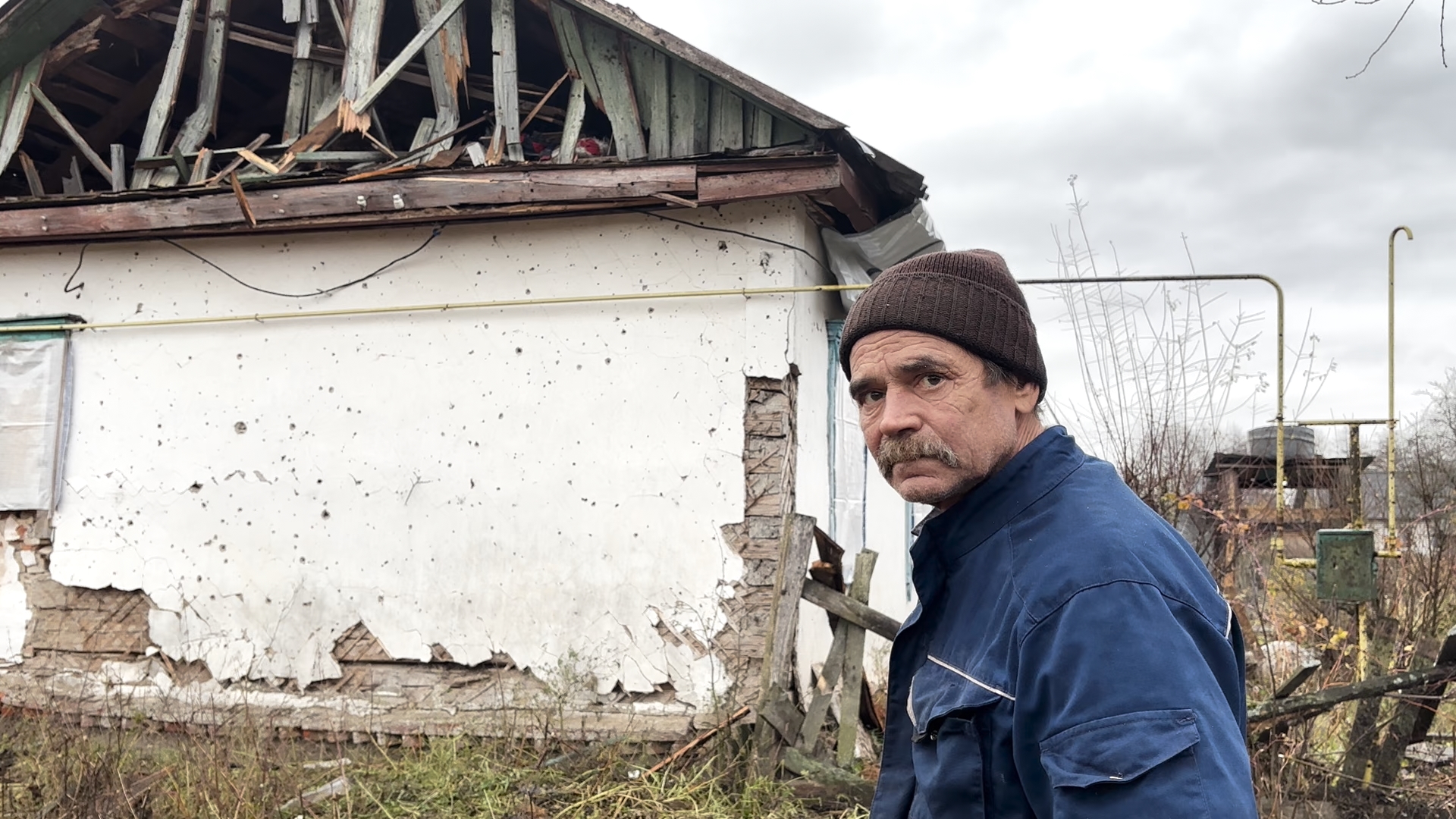 Володимир Каух біля свого побитого будинку