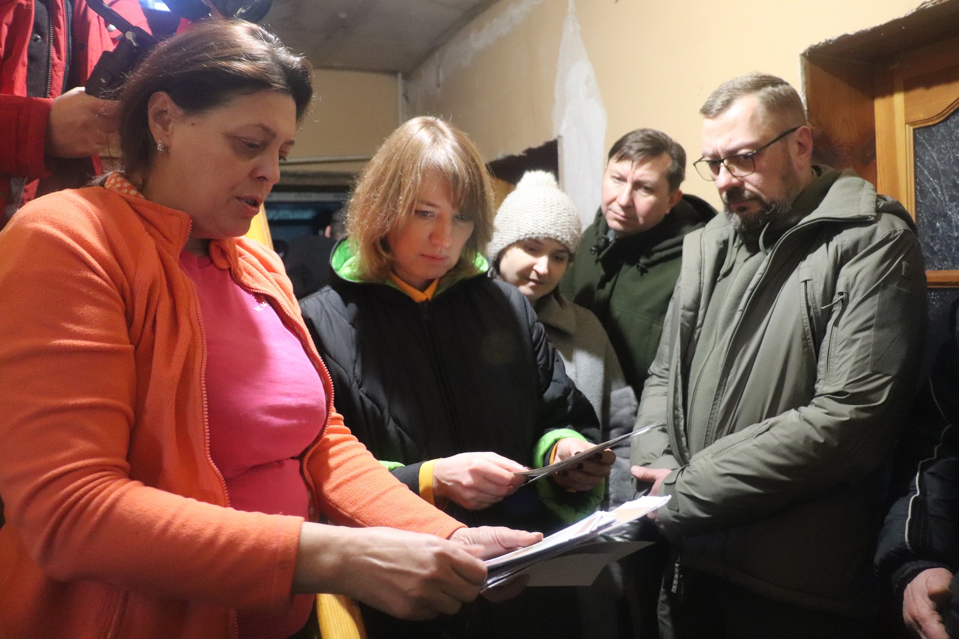 Пані Ірина показує чиновникам фото руйнувань
